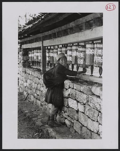 Boy standing in front of row of prayer wheels - Sikkim (c1965-71)