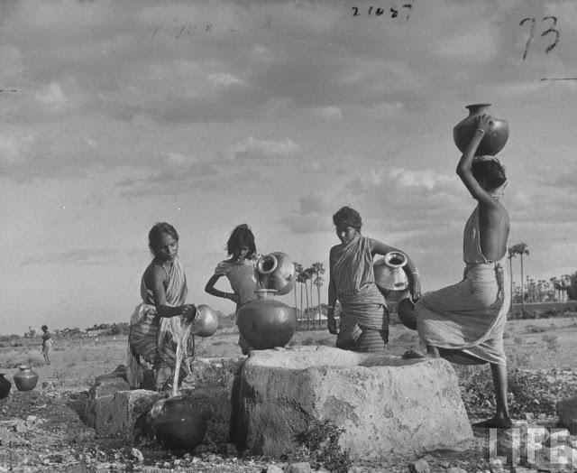 Indian Village Women Pouring water from village well into their Jugs to be Carried on their Head back to their Meager Homes - Poodalur, India 1946